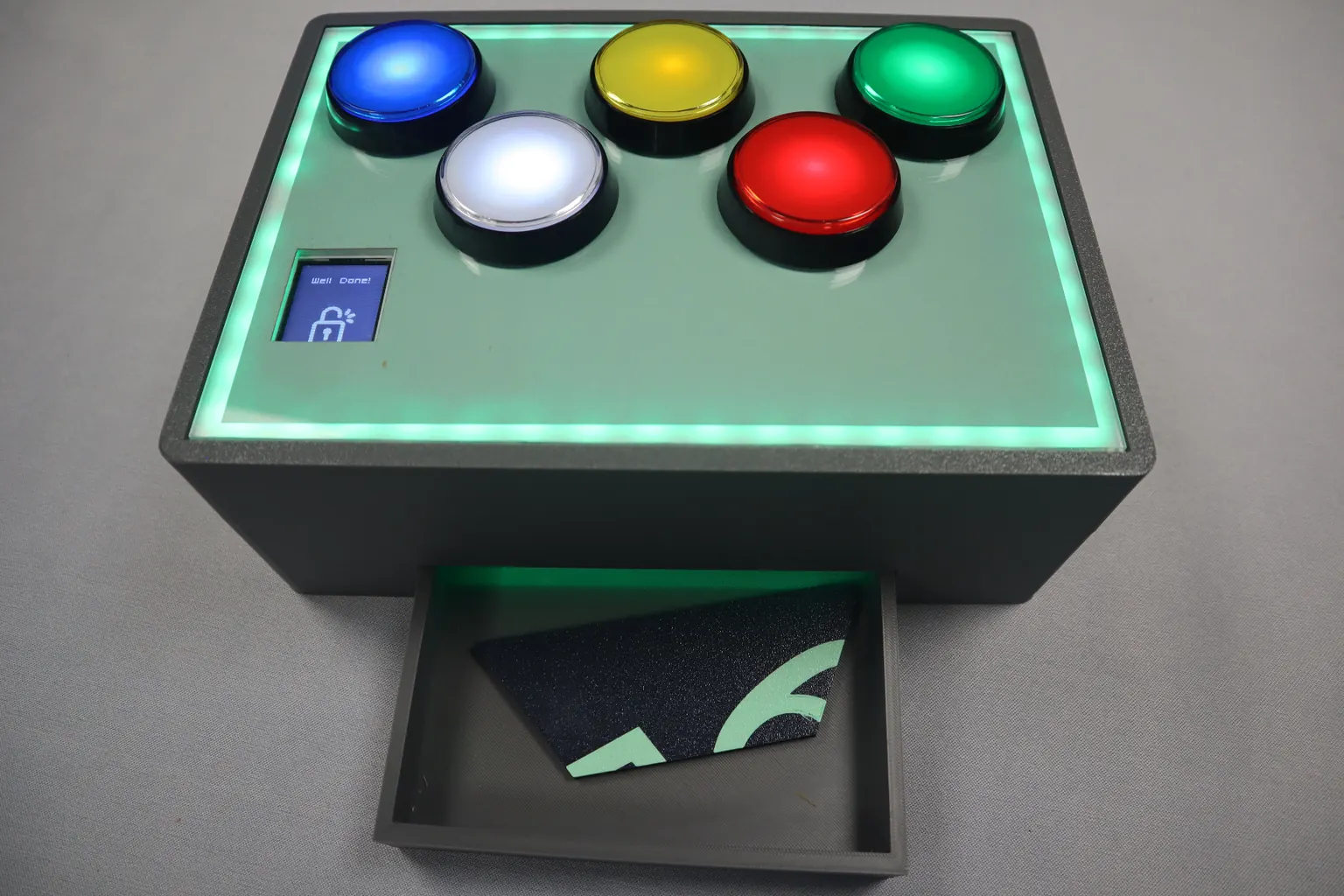 UNPACK electronic puzzle module showing illuminated buttons, LED surround, screen display and built-in drawer